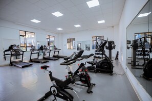Ein Fitnessraum mit verschiedenen Trainingsgeräten, darunter Laufbänder, Ergometer und Kraftgeräte.