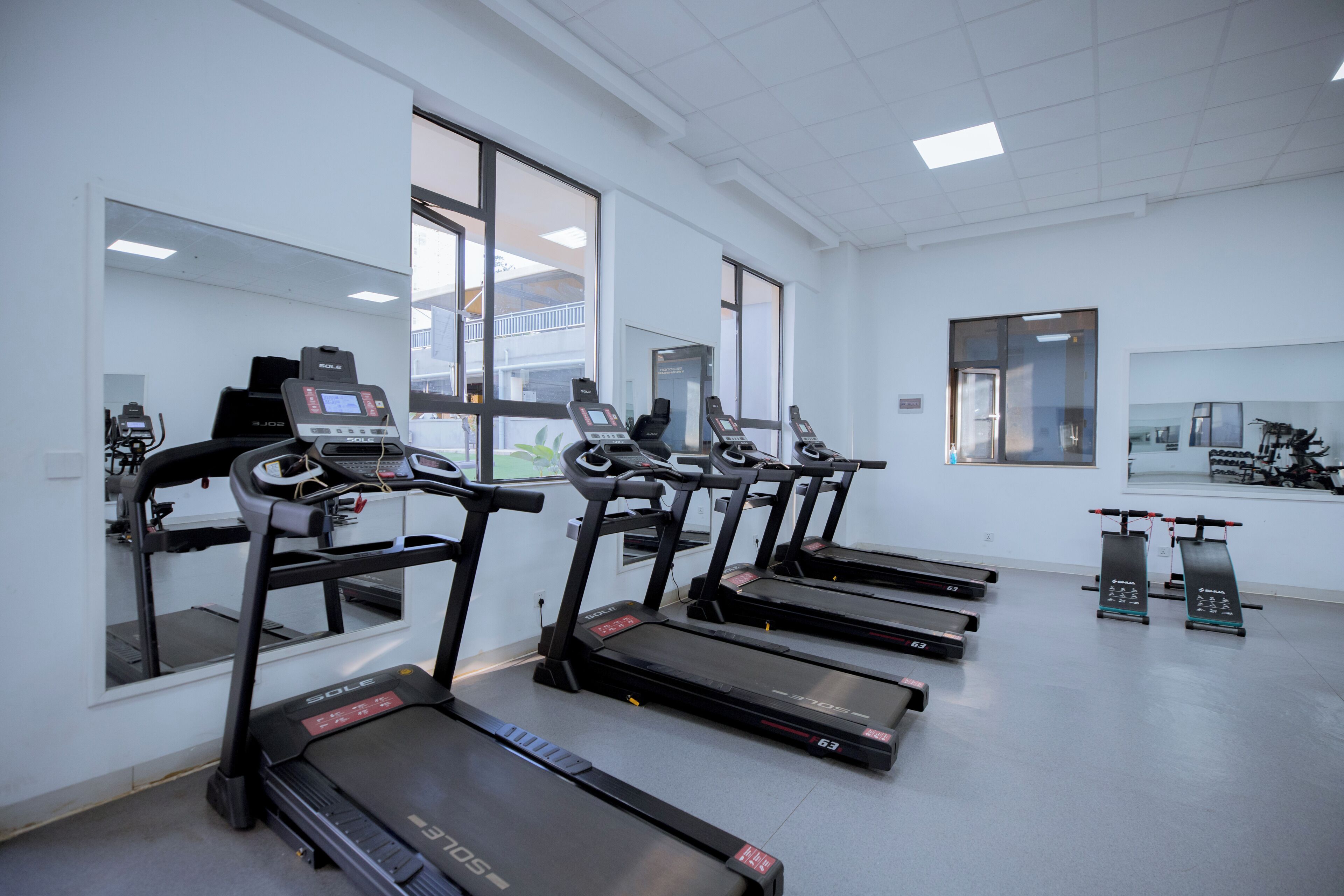 A fitness center with treadmills, exercise bikes, and a mirrored wall.