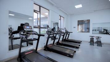 A fitness center with treadmills, exercise bikes, and a mirrored wall.