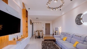 Una sala moderna con televisor de pantalla plana, un sofá, una mesa de centro y un comedor con sillas.
