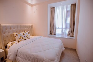 Une chambre à coucher avec un grand lit, une table de chevet et une fenêtre avec des rideaux.