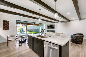 A modern kitchen with a large island, dark cabinetry, and pendant lighting. - Havasu Mcculloch - Luxury Feel, Luxury Stay (Lake Havasu City)