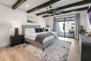 Une chambre moderne avec un grand lit, un ventilateur de plafond et une vue sur un patio extérieur.
