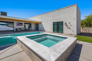 Une maison moderne dotée d’une piscine, d’un patio avec mobilier d’extérieur et d’une grande fenêtre.