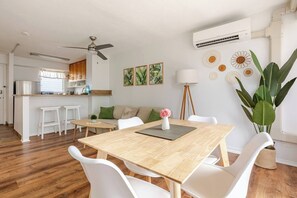 A modern living space with a dining area, kitchen, and a ceiling fan. - New Waikiki 2BR •Walk to Beach +free parking (Honolulu)