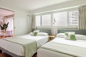 Une chambre d’hôtel avec deux lits, un bureau et une chaise.