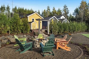 A yellow cabin with a stone fire pit and outdoor seating. - Seabrook Cottage - Couples + Small Families, BBQ, Indoor & Outdoor Fire (Pacific Beach)