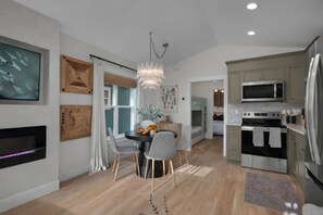 A modern kitchen with a dining area, a built-in microwave, and a refrigerator. - Seabrook Cottage - Couples + Small Families, BBQ, Indoor & Outdoor Fire (Pacific Beach)