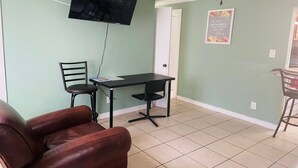 A living room with a TV mounted on the wall, a dining table with two chairs, and a sofa. - Aparment Downtown Sarasota 2br, 2ba, Petfriendly Beaches, 5 People (Sarasota)