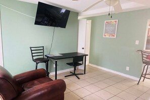 A living room with a TV mounted on the wall, a dining table with two chairs, and a sofa. - Aparment Downtown Sarasota 2br, 2ba, Petfriendly Beaches, 5 People (Sarasota)