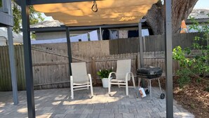 A covered patio area with a wooden fence, two white chairs, a grill, and a potted plant. - Aparment Downtown Sarasota 2br, 2ba, Petfriendly Beaches, 5 People (Sarasota)