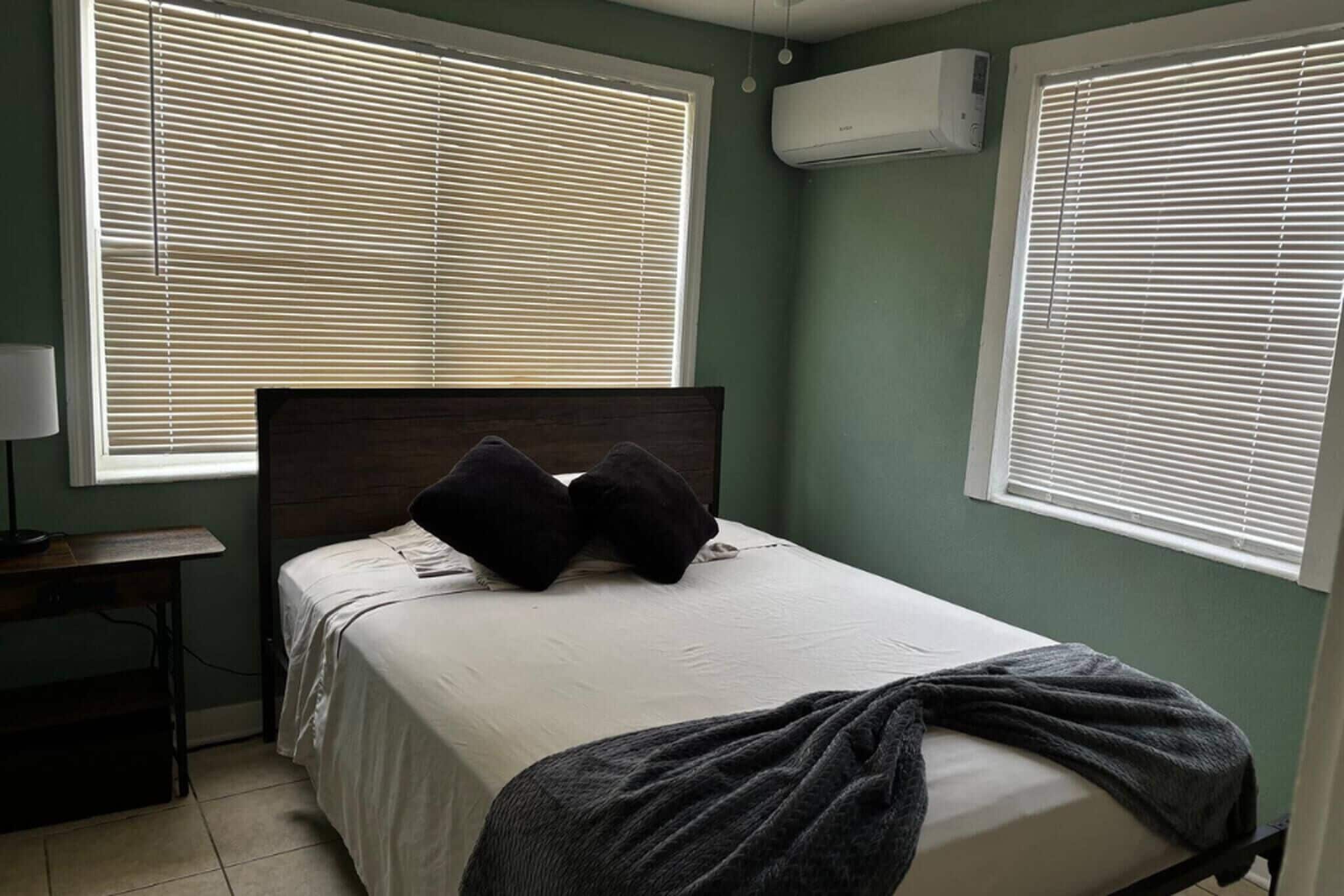 Une chambre à coucher avec un lit, deux oreillers, une table de chevet et une lampe.