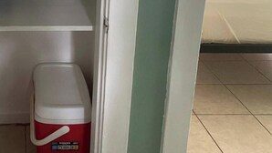 A hotel room with a bed, a shelf with folded towels, and a red cooler. - Aparment Downtown Sarasota 2br, 2ba, Petfriendly Beaches, 5 People (Sarasota)