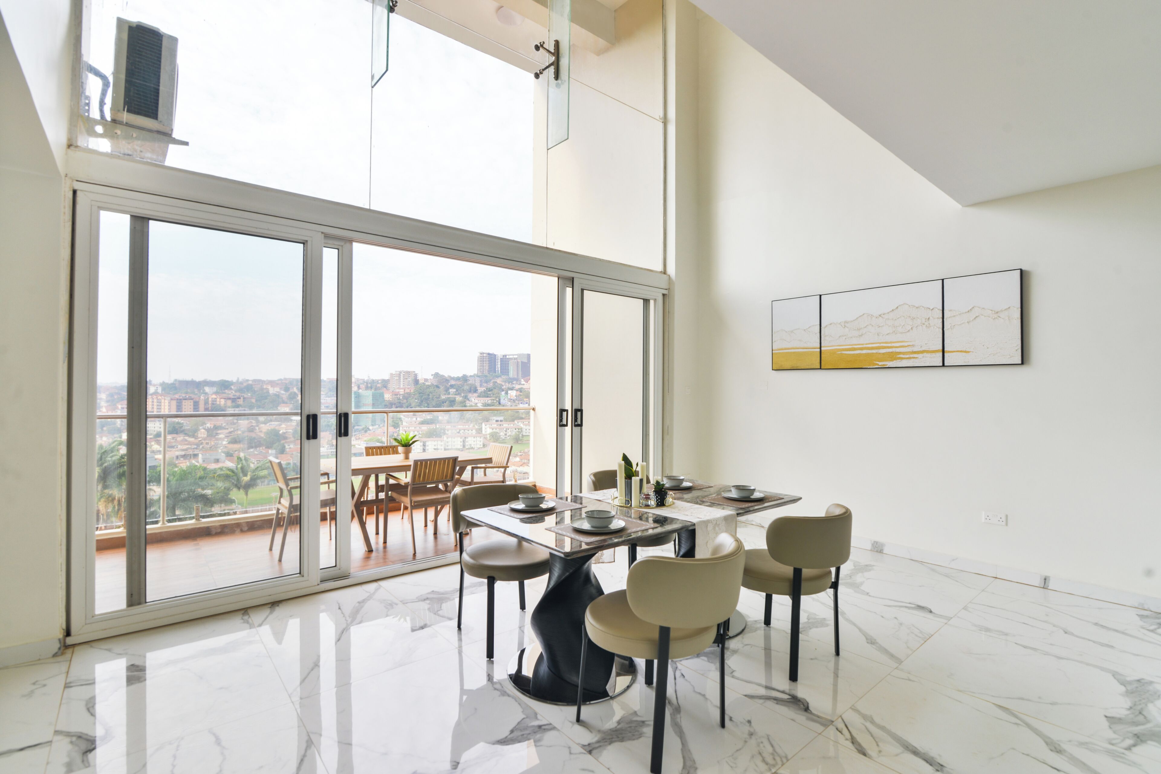 Comedor con una gran mesa, sillas y vistas a la ciudad a través de un ventanal.