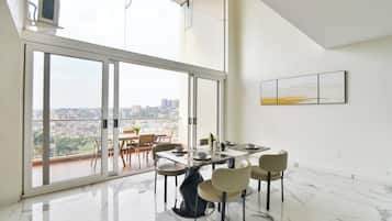 Comedor con una gran mesa, sillas y vistas a la ciudad a través de un ventanal.