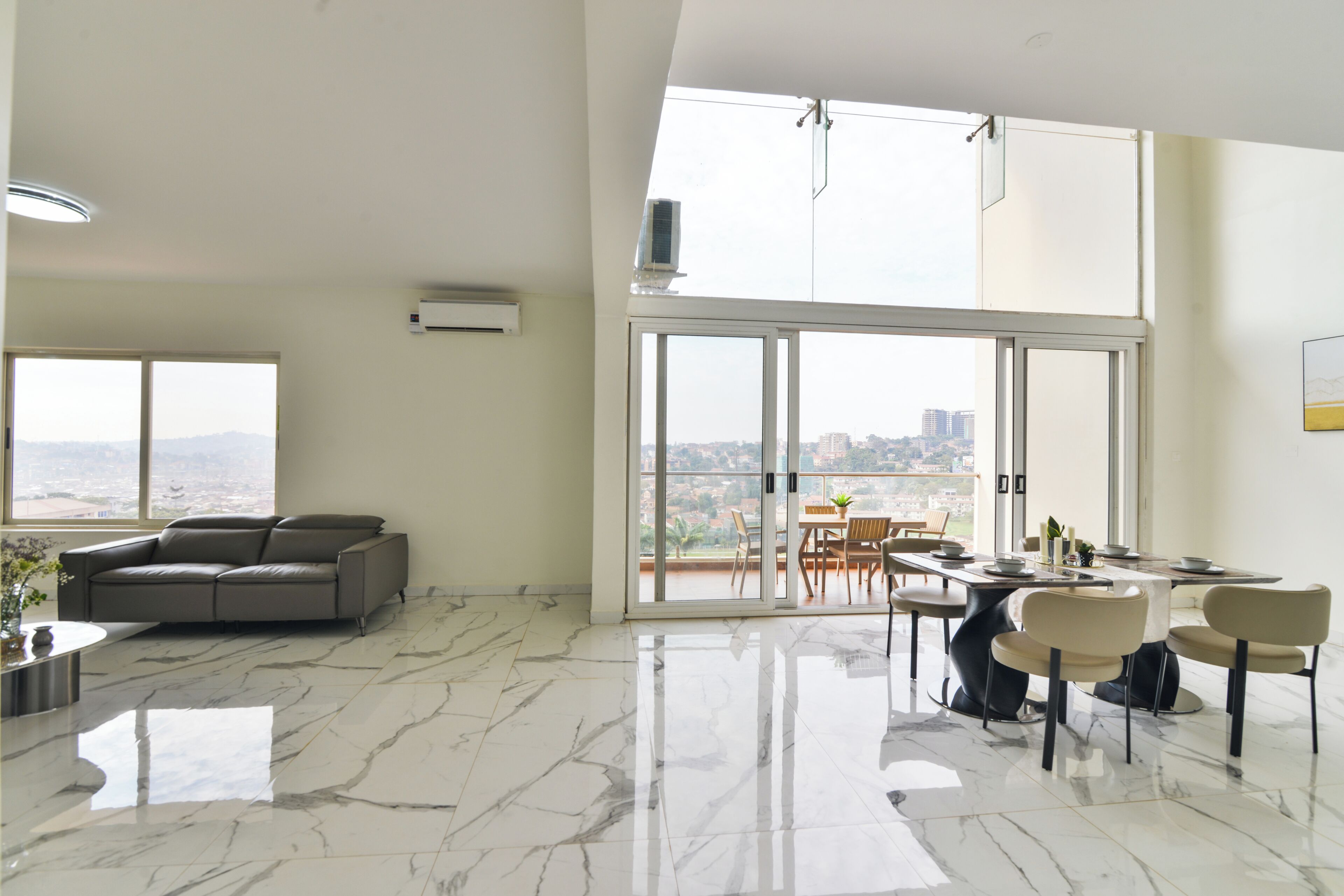 Un amplio espacio de estar con un ventanal grande, un sofá y una mesa de comedor con sillas.