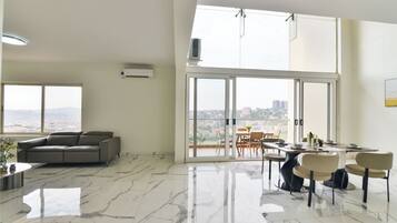 Un amplio espacio de estar con un ventanal grande, un sofá y una mesa de comedor con sillas.