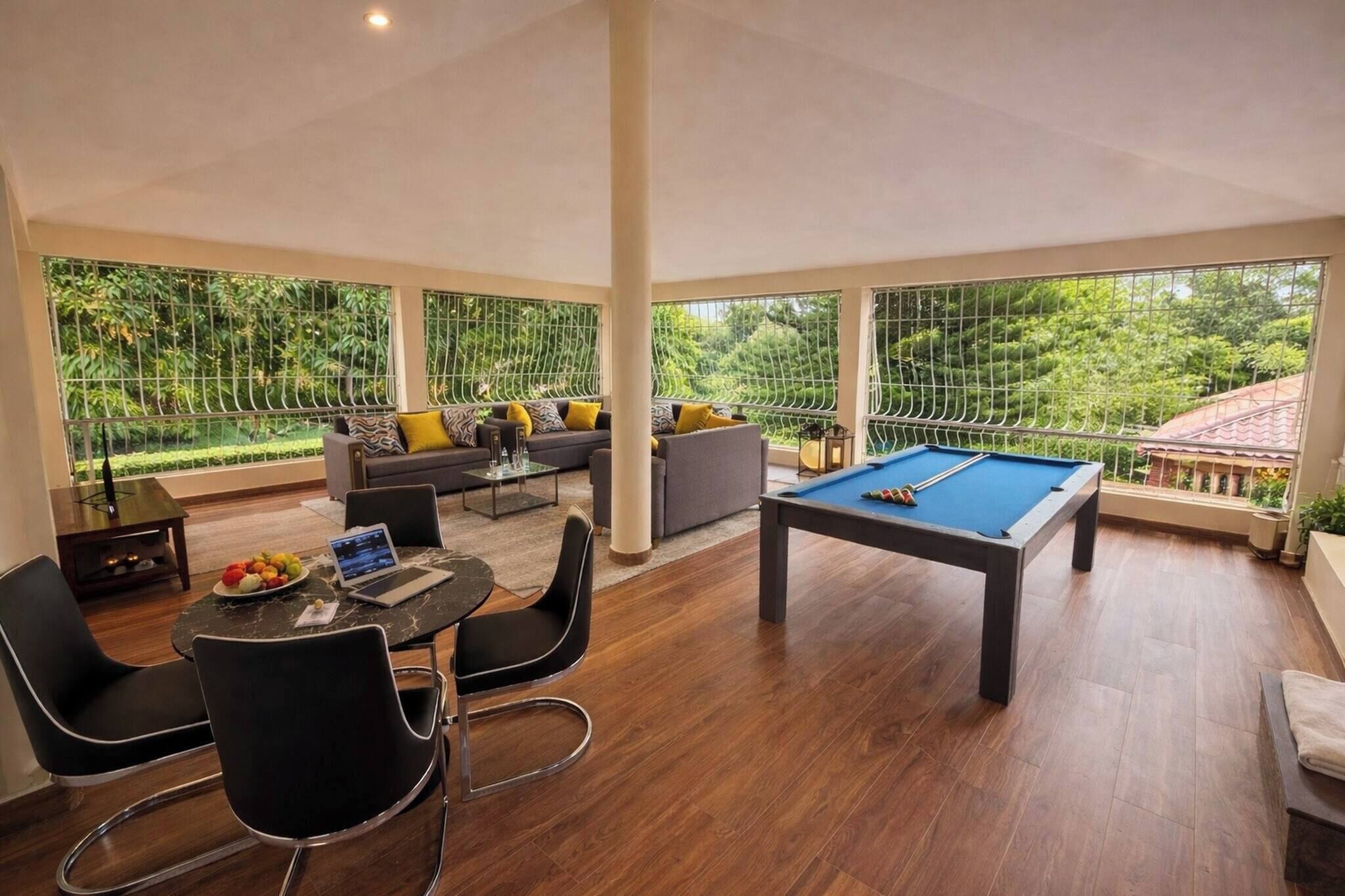 A spacious room with a pool table, a dining area with chairs and a table, and a sofa set.