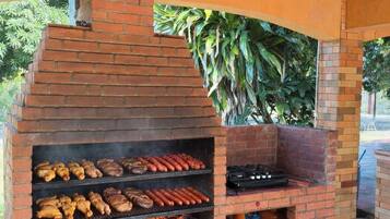 Ein gemauerter Grill für den Außenbereich mit mehreren Kochzonen und einem Gasflasche darunter.