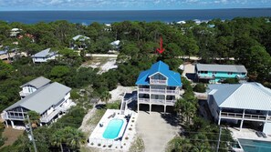 A coastal property with a large house featuring a blue roof, a swimming pool, and a view of the ocean. - The Blue Pelican New-SGI- POOL - Sleeps 12 (Eastpoint)