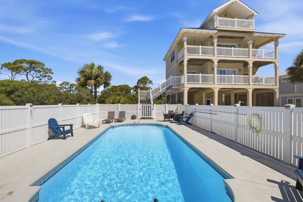 A two-story building with a swimming pool, white railings, and a white fence. - The Blue Pelican New-SGI- POOL - Sleeps 12 (Eastpoint)