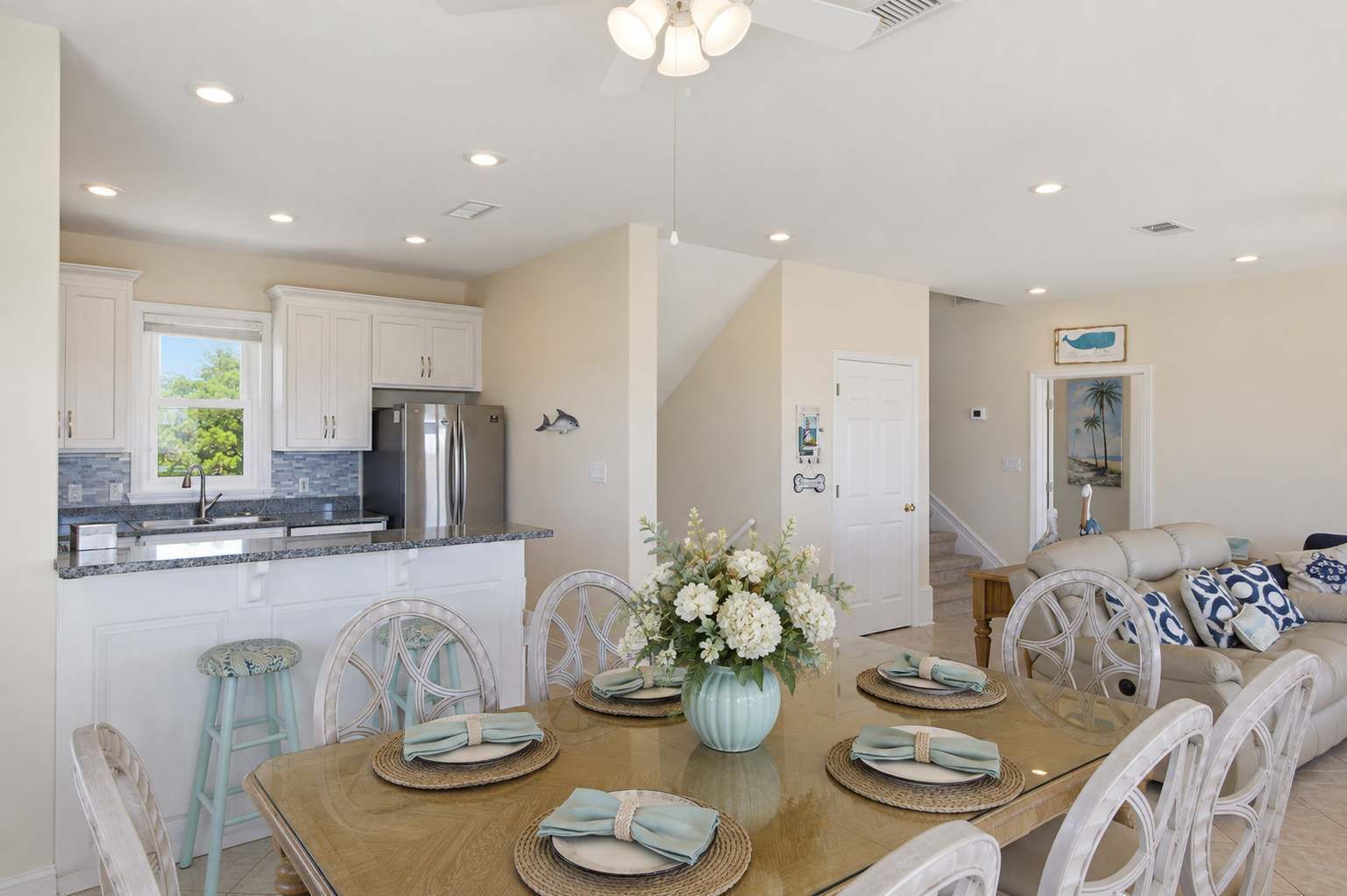 A modern kitchen with white cabinets, stainless steel appliances, and a dining area with a wooden table set for four.
