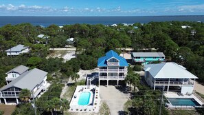 A coastal residential area with multiple houses, a large swimming pool, and a view of the ocean. - The Blue Pelican New-SGI- POOL - Sleeps 12 (Eastpoint)