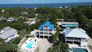 A large two-story house with a swimming pool, surrounded by dense trees and a view of the ocean. - The Blue Pelican New-SGI- POOL - Sleeps 12 (Eastpoint)