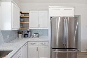 Eine Küche mit weißen Schränken, einem Edelstahl-Kühlschrank, einer Kaffeemaschine und einem Toaster.