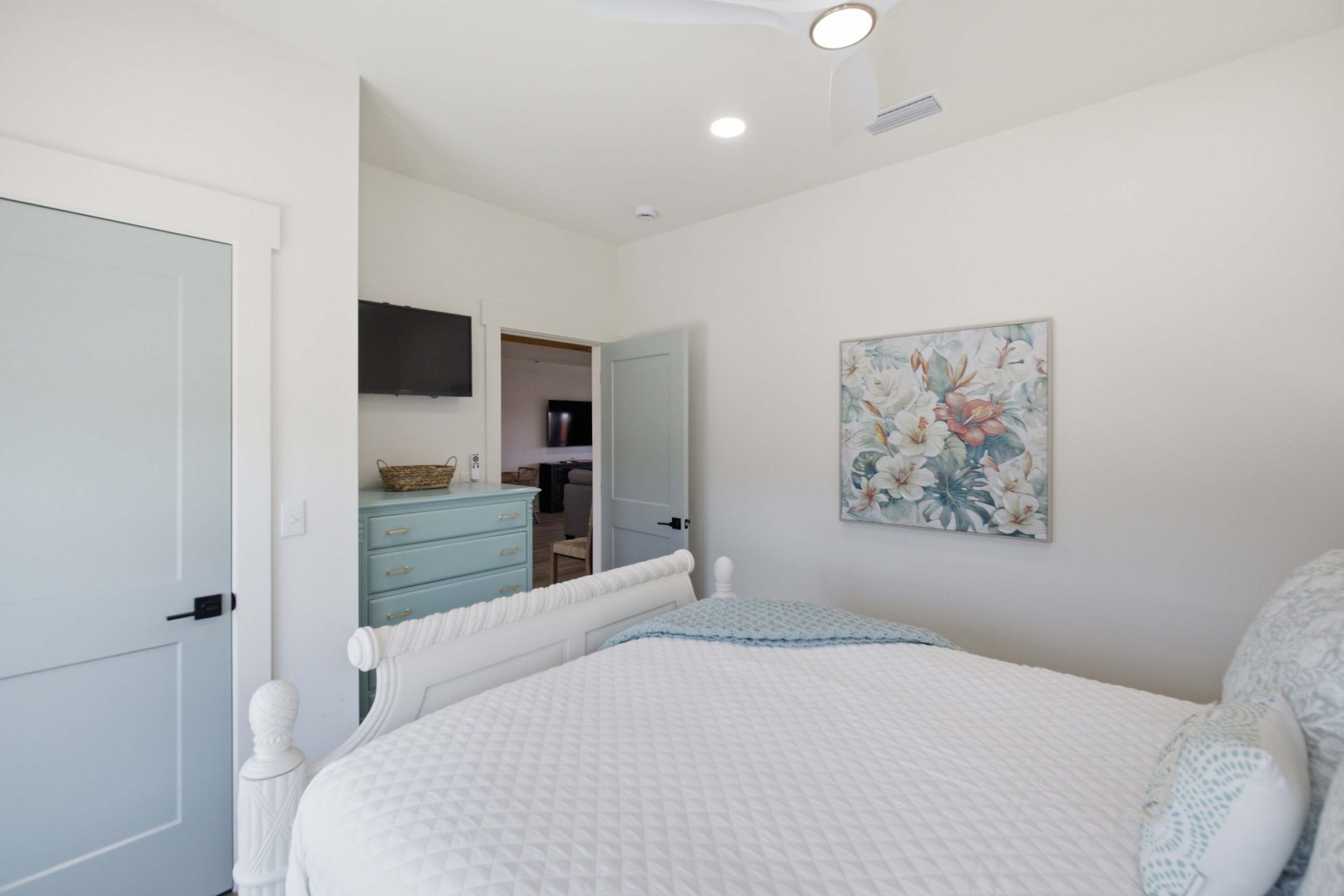A bedroom with a bed, a dresser, a television, and a door.