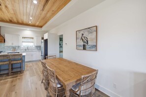 Una cocina amplia con armarios de madera, una isla central y un comedor con mesa de madera y sillas de mimbre.