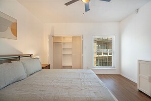 A bedroom with a bed, a ceiling fan, a window with blinds, and a walk-in closet. - King Bed: Workspace & Walk to Dog Park (Dallas)