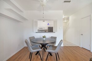 A dining area with a round table, four chairs, a ceiling fan, and a kitchen with a microwave and refrigerator. - King Bed: Workspace & Walk to Dog Park (Dallas)