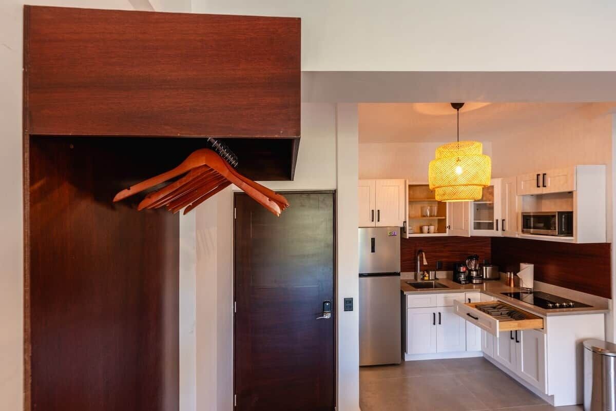 A modern kitchen with white cabinets, a stainless steel refrigerator, and a hanging light fixture.
