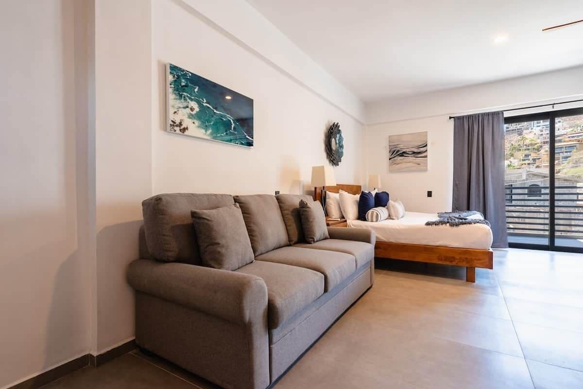 Une chambre à coucher moderne avec un canapé, un lit et des œuvres d’art accrochées aux murs.