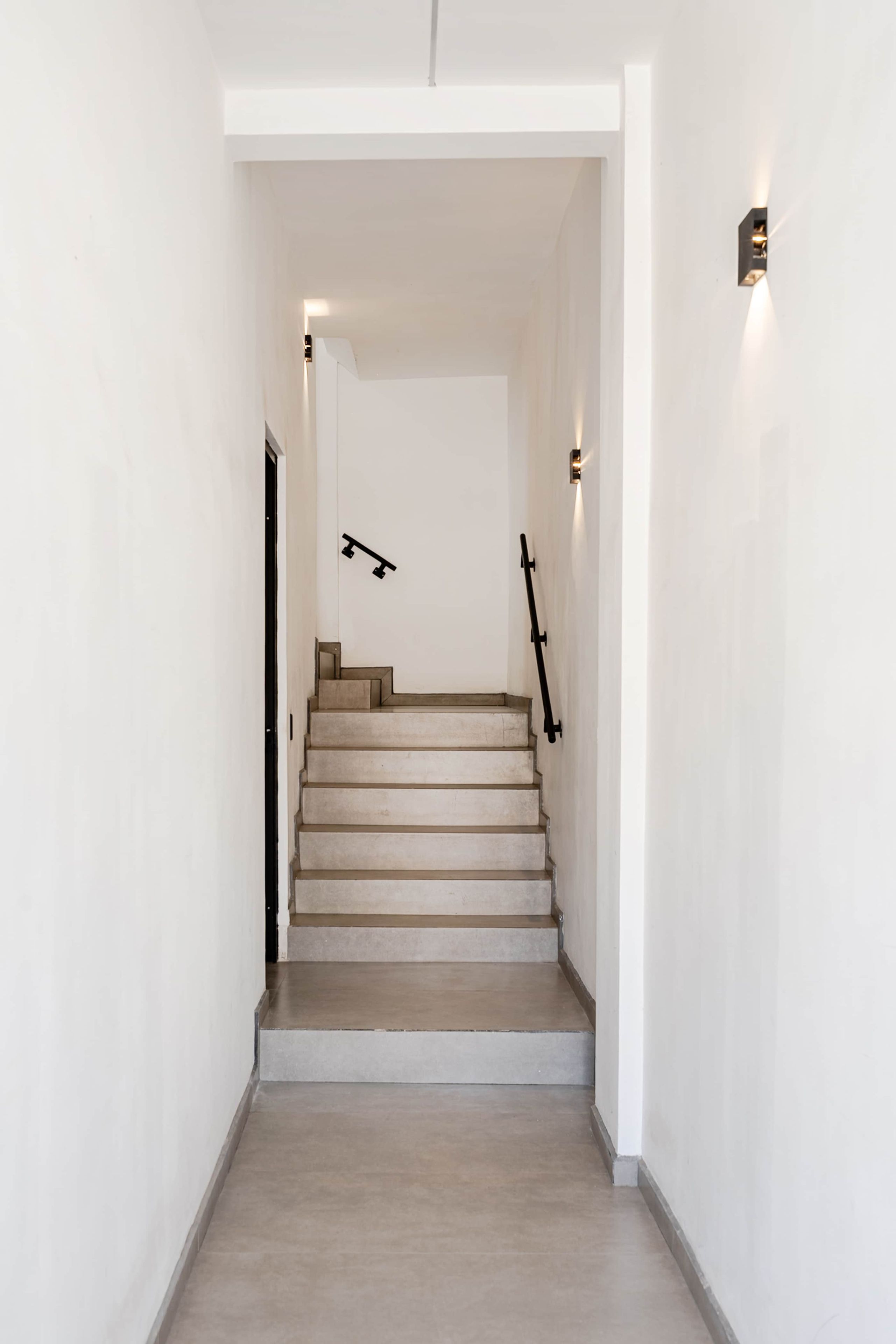 A staircase with a handrail, leading to a landing with a door.