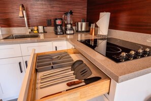 Uma cozinha com fogão embutido, cafeteira e liquidificador.