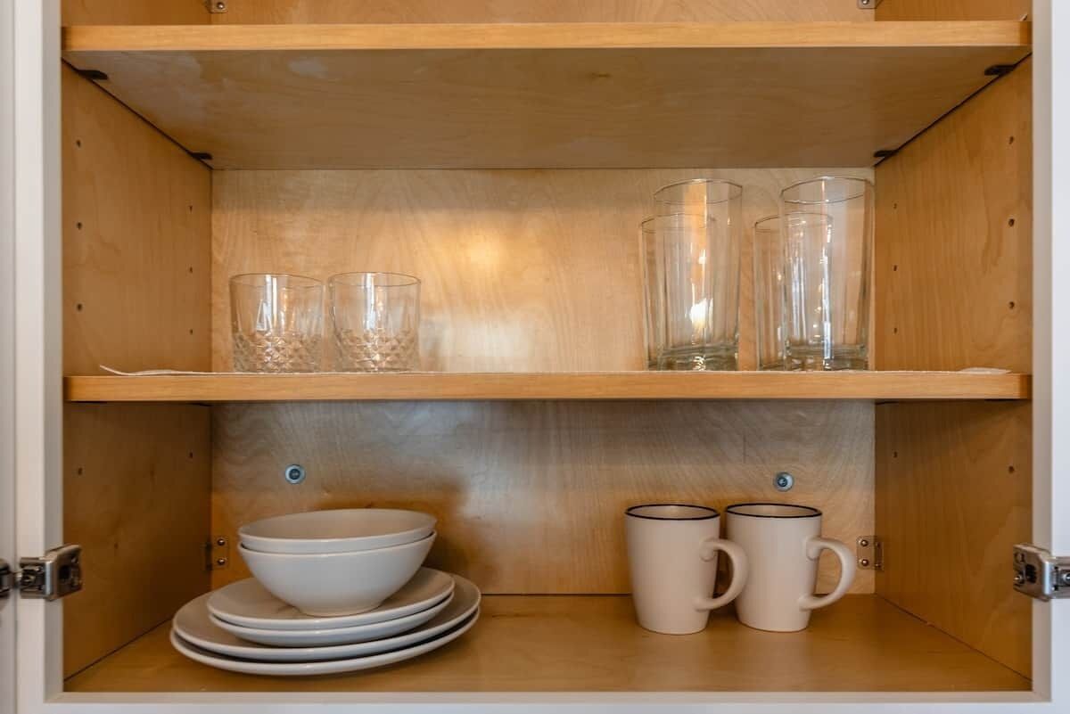 Un meuble en bois doté d’étagères où sont rangés des verres et des bols transparents.