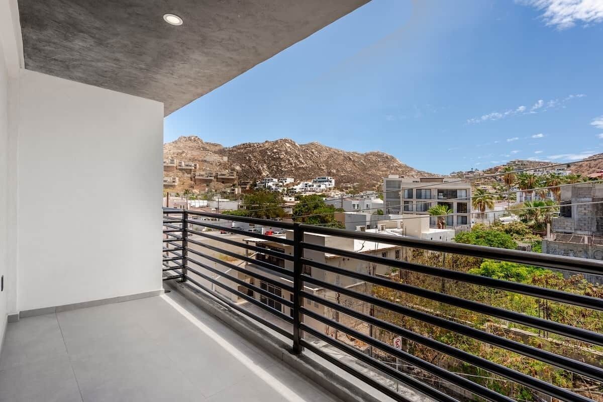 A balcony with a view of a mountainous landscape and residential buildings.