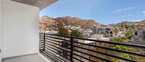 A balcony with a view of a mountainous landscape and residential buildings.