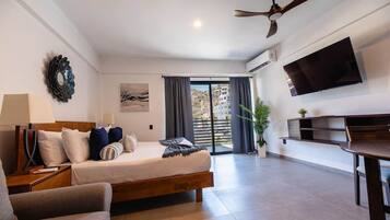 Une chambre d’hôtel équipée d’un lit, d’un bureau, d’une chaise, d’une télévision, d’un ventilateur de plafond et offrant une vue sur l’extérieur.