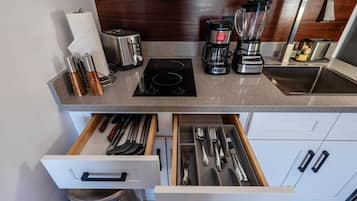 Une cuisine équipée d’un grille-pain, d’une machine à café, d’un mixeur et d’un évier. On y trouve des ustensiles dans un tiroir, ainsi qu’un rouleau d’essuie-tout.