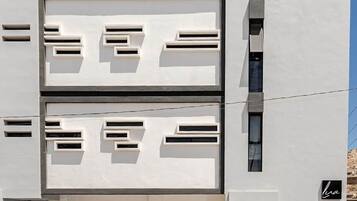 Un bâtiment moderne à la façade plate, doté de nombreuses fenêtres et comprenant un parking avec des voitures.