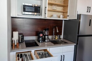 Eine moderne Küche mit Mikrowelle, Toaster, Kaffeemaschine, Mixer und Edelstahlgeräten.