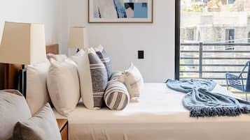 Een moderne slaapkamer met een bed, kussens, een bank, een raam met uitzicht en een airconditioning.