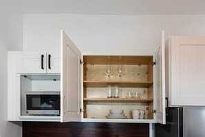 Une cuisine équipée d’un four à micro-ondes, de placards ouverts et d’un réfrigérateur.