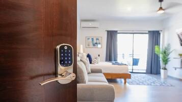 Une chambre d’hôtel moderne dotée d’une serrure à clavier numérique, d’un canapé, d’un lit et d’une grande fenêtre avec des rideaux.