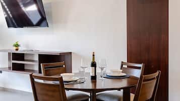 Un comedor moderno con una mesa redonda, cuatro sillas, un televisor montado en la pared y un mueble de madera.