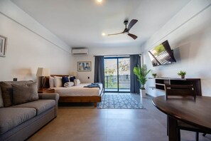 A hotel room with a bed, a sofa, a dining table, a TV, and a ceiling fan. - New Listing • Prime Location • Cozy & Modern (Cabo San Lucas)