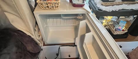 Una kitchenette compacta con cafetera, microondas y refrigerador pequeño.